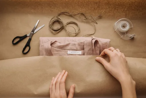An order being wrapped with kraft paper, scissors and twine